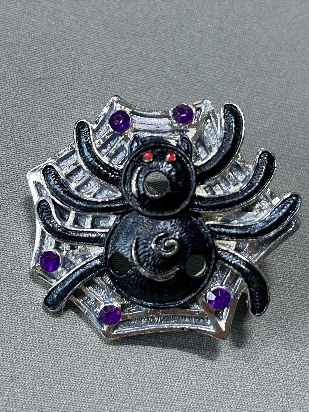 Spooky silver and black metal spider pin for Halloween.